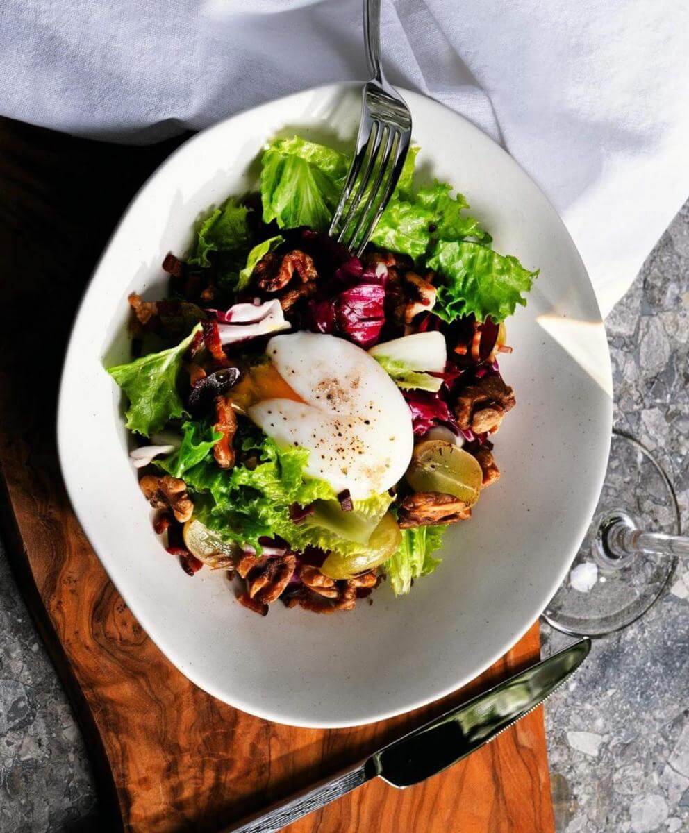 Salade d'œufs pochés sous vide avec vinaigrette chaude au bacon